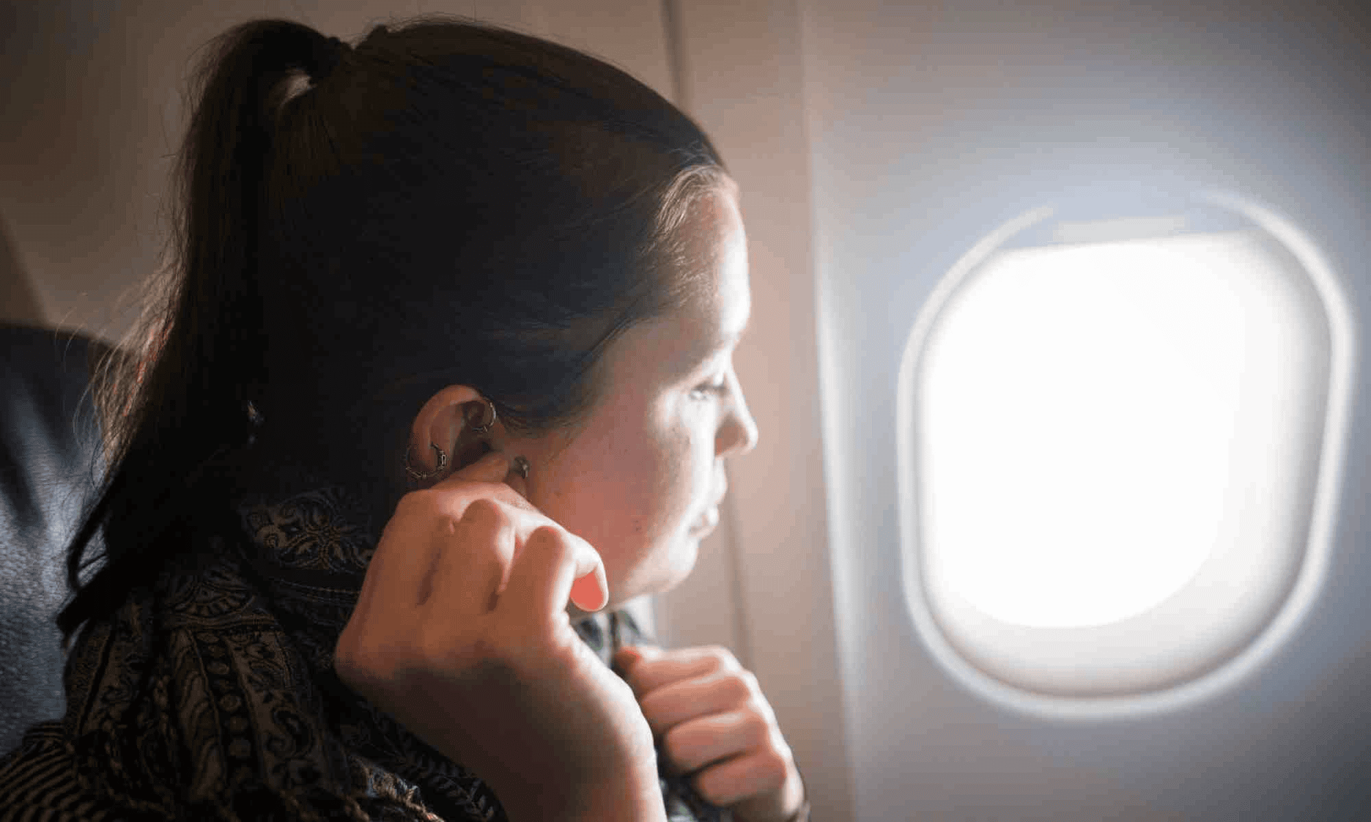 Women inserting earphone in her ear on airplane